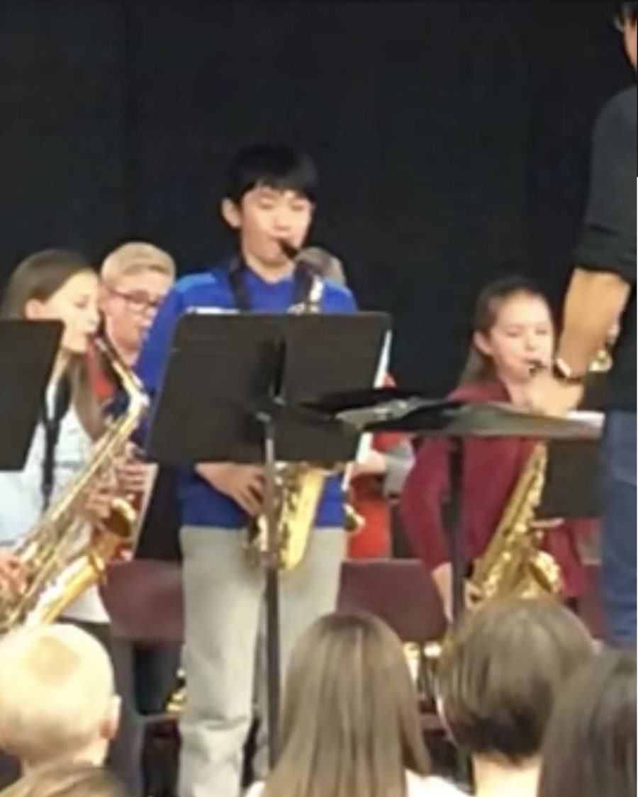 Young Ethan standing to play a saxophone solo with his band